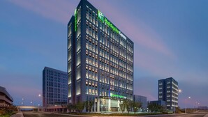 Un hotel de varios pisos con un llamativo letrero de 'Holiday Inn Express', ventanas amplias y un diseño arquitectónico moderno.