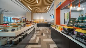 A buffet area with a variety of food options, a counter with a digital menu, and a patterned floor. - Holiday Inn Express Rongcheng Science And Technolo (Weihai)