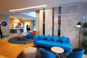 Relax in the stylish lobby with a comfortable sofa and seating area, featuring a reception desk and modern design.