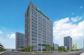 A modern hotel building with a prominent green sign, multiple floors, and a clear sky. - Holiday Inn Express Rongcheng Science And Technolo (Weihai)