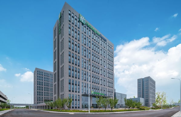 A modern hotel building with a prominent green sign, multiple floors, and a clear sky. - Holiday Inn Express Rongcheng Science And Technolo (Weihai)