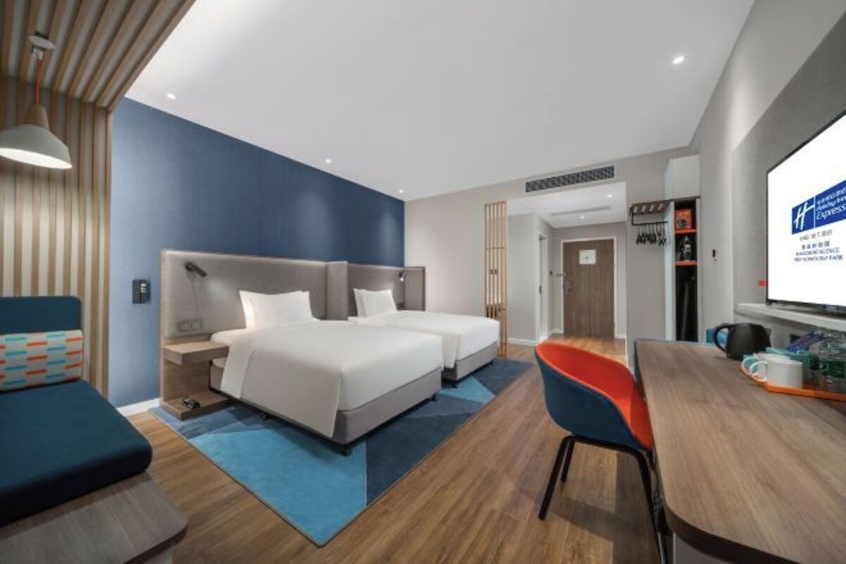 Una camera d'albergo moderna con due letti, una scrivania e una sedia.