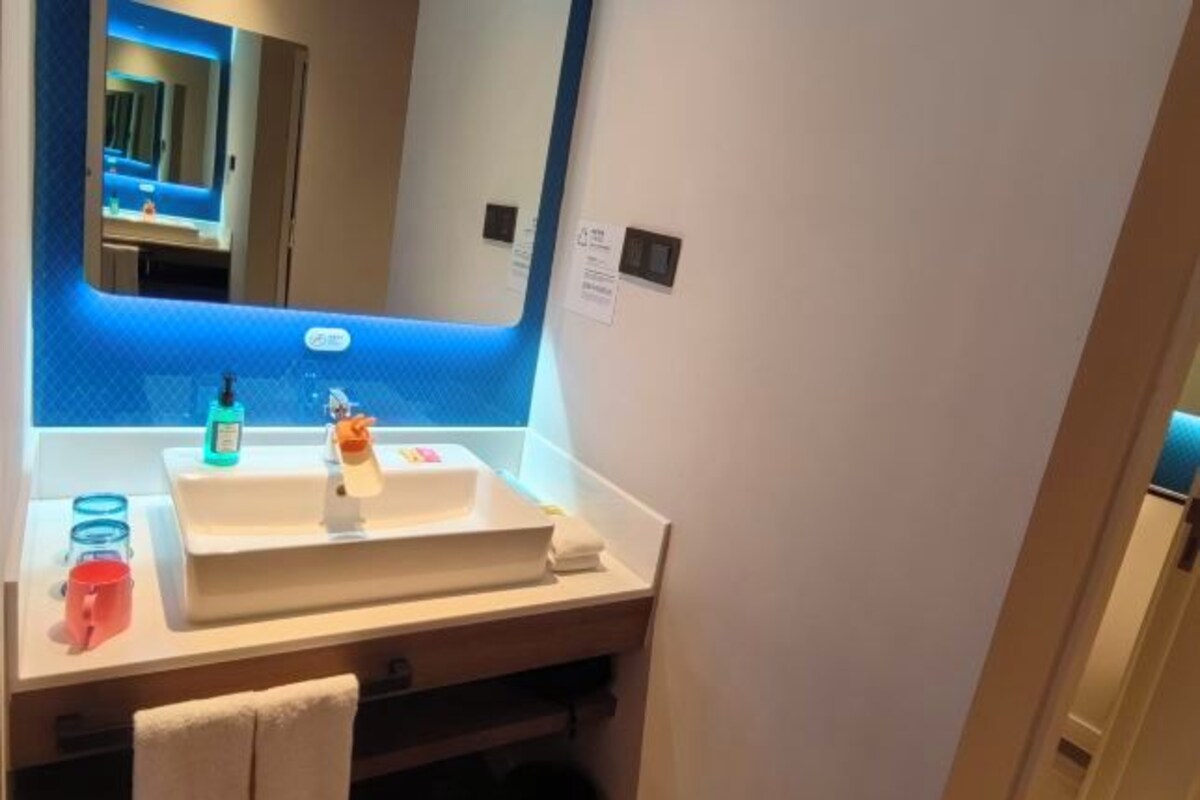Un bagno moderno con uno specchio grande, un lavandino bianco e una parete azzurra.