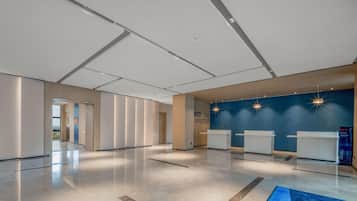 Un hall amplio con mostrador de recepción, una pared azul de acento y suelo pulido.