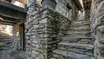 A stone staircase leading up to a wooden door, with a metal basket and a chair on the steps.