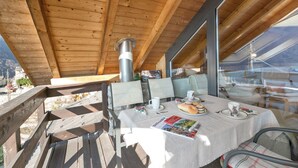 A wooden deck with a table set for two, featuring a magazine, a plate with food, and cups.