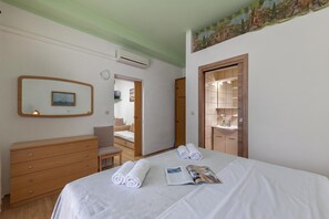 A hotel room with a bed, a wooden dresser, a mirror, and a door leading to a bathroom. - Oasis of Peace in Lopar /w Terrace, Lopar, Croatia (Lopar)