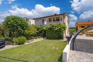 A two-story house with a balcony, surrounded by a well-maintained lawn and various plants. - Oasis Of Peace In Lopar, Lopar, Croatia (Lopar)