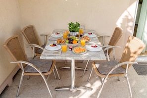 A dining table with chairs, plates, bowls, and glasses of juice. - Oasis of Peace in Lopar /w Terrace, Lopar, Croatia (Lopar)