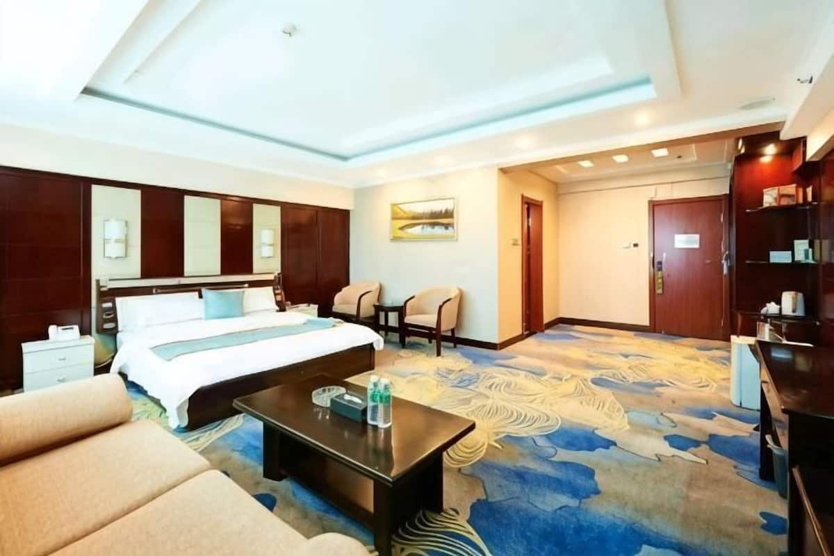 A hotel room with a bed, a coffee table, a sofa, a desk, and a bookshelf.