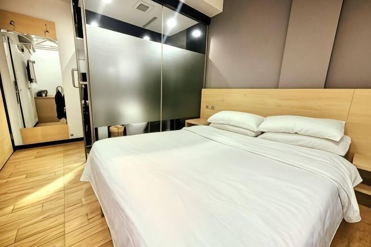 A modern hotel room with a large bed, a mirror, and a wooden floor.