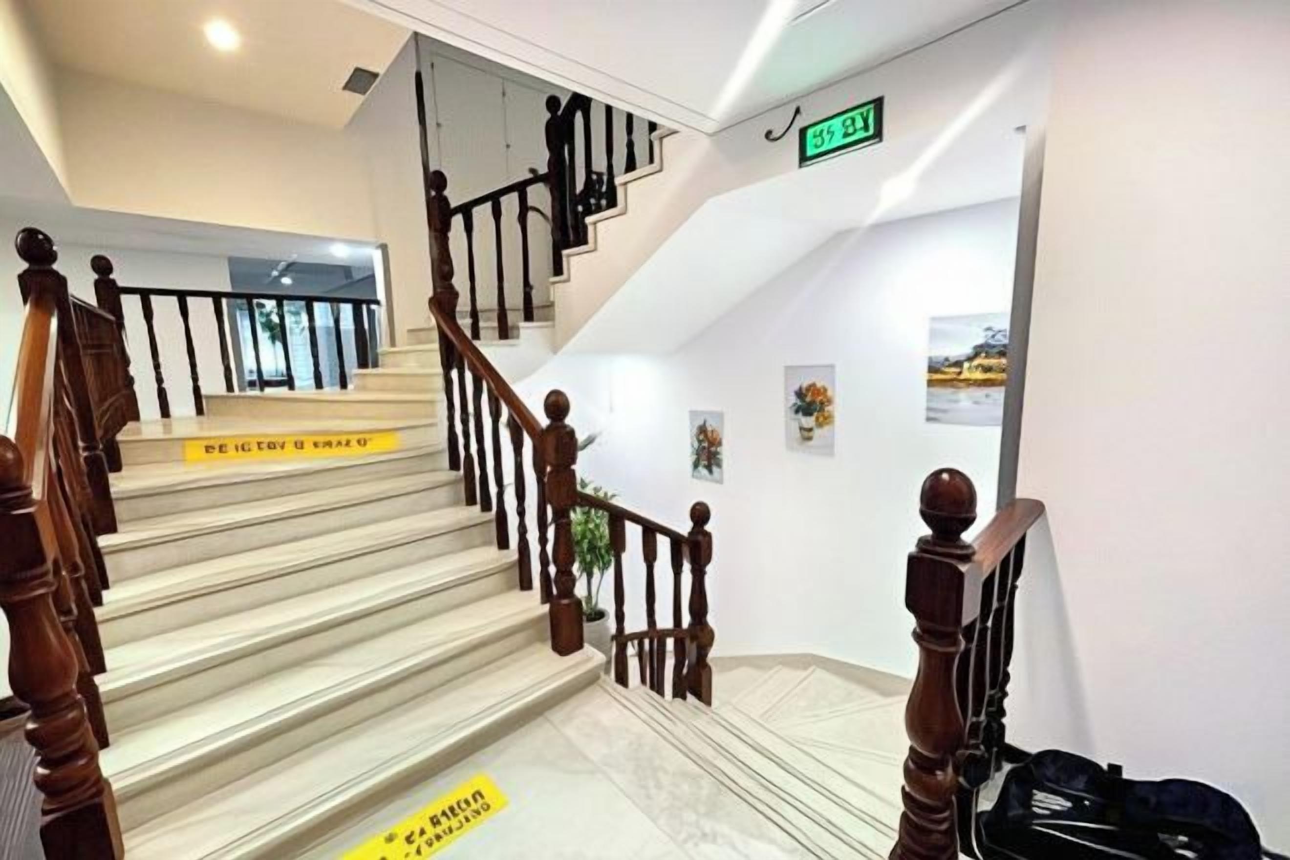 A staircase with wooden railings and a handrail, leading to a landing with a sign.