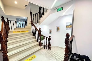 Una escalera con barandas de madera y pasamanos, que conduce a una plataforma con un letrero.