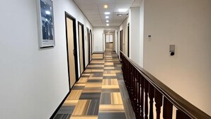A hotel corridor with a checkered floor, doors on one side, and a railing on the other. - Hi Inn (Shanghai Jinshan Zhujing Jinlong New Street) (Shanghai)