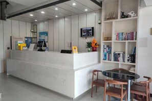 A reception area with a reception desk, a television mounted on the wall, and a bookshelf with books and decorative items. - Hi Inn (Shanghai Jinshan Zhujing Jinlong New Street) (Shanghai)