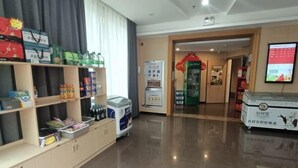 A hotel lobby with a reception desk, a vending machine, and shelves stocked with various items. - Shankee Hotel (Qingdao Development Zone Xiangjiang Second Road) (Qingdao)