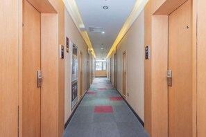 A hotel hallway with wooden doors, a carpeted floor, and a ceiling light. - Shankee Hotel (Qingdao Development Zone Xiangjiang Second Road) (Qingdao)