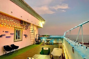 An outdoor deck with seating, a table, and a view of the sea. - Tianlun Hotel Shanwei Honghaiwan (Shanwei)