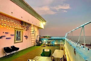 Una terraza exterior con asientos, una mesa y vista al mar.