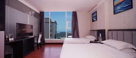 Quarto de hotel com uma janela grande, uma escrivaninha com televisão, duas camas e um quadro na parede.