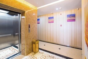An elevator with a marble wall and a patterned floor. - Tianlun Hotel Shanwei Honghaiwan (Shanwei)