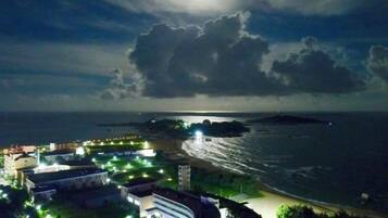 Vista costera con edificios, una playa y una extensión de agua bajo un cielo nublado.