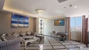 Una sala moderna con sofá, mesa de centro y mesa de billar. Amplias ventanas con vistas a la ciudad.