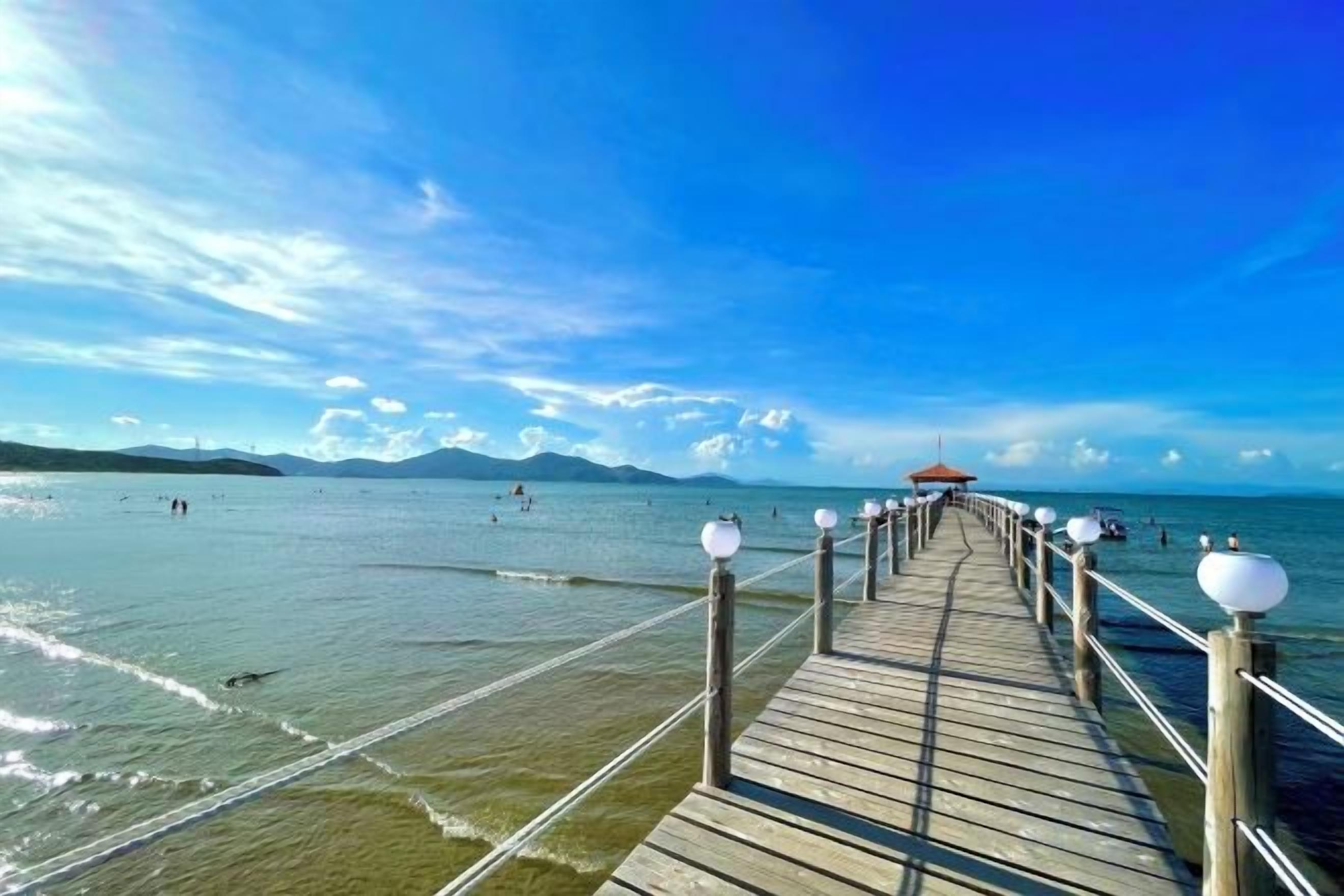 A wooden pier extending into a body of water with a clear sky above.