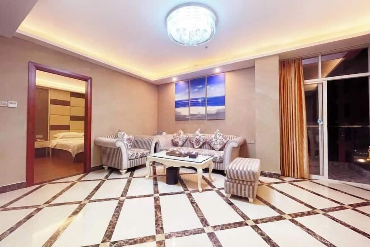 Habitación de hotel con una cama grande, un sofá, una mesa de centro y vistas al exterior.