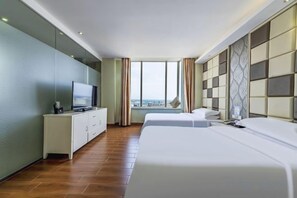 A hotel room with a bed, a TV on a white cabinet, a large window, and a city view. - Tianlun Hotel Shanwei Honghaiwan (Shanwei)