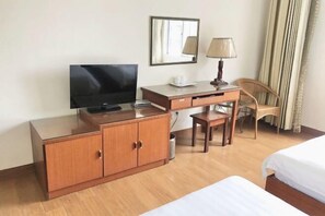 A hotel room with a wooden desk, a television, a lamp, a chair, and a bed. - Riyuehe Hostel (Beihai)