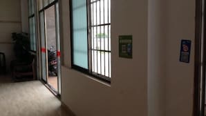 A hallway with large windows, a door, and a wall-mounted sign. - Riyuehe Hostel (Beihai)