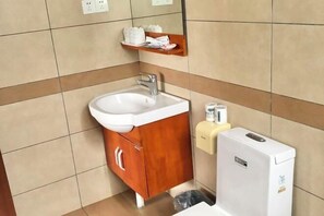 A bathroom with a sink, mirror, wooden cabinet, and a hand dryer. - Riyuehe Hostel (Beihai)