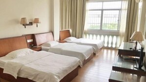 A hotel room with two beds, a desk, and a window with curtains. - Riyuehe Hostel (Beihai)