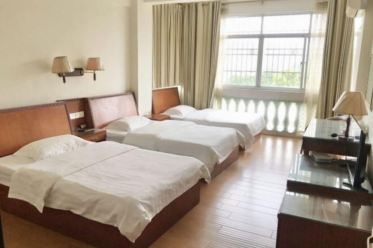 A hotel room with two beds, a desk, and a window with curtains.