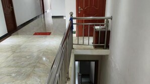 A marble-floored corridor with a metal railing and a red door at the end. - Honghelou Hotel, Wuhu (Wuhu)