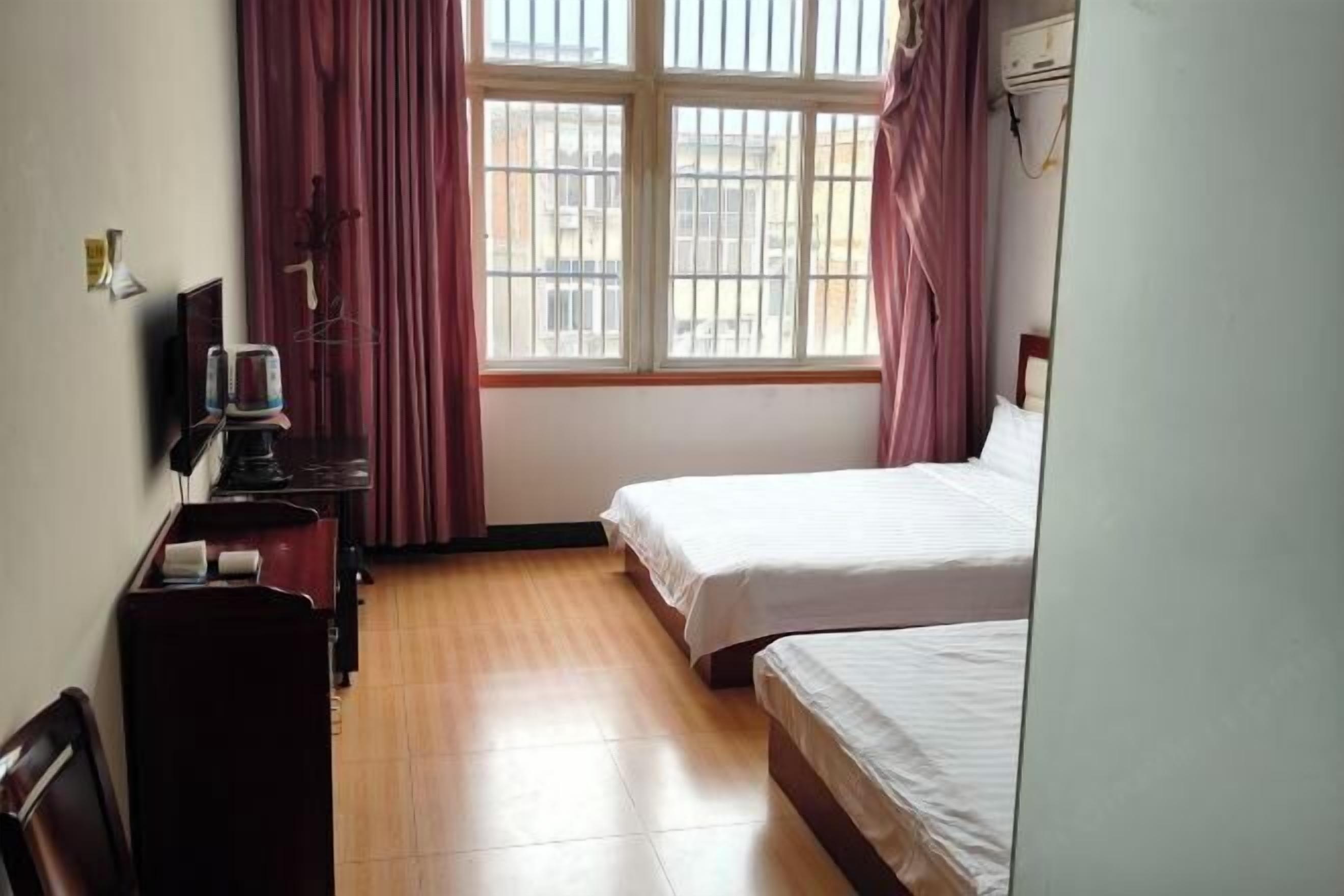 Una habitación de hotel con una cama, un escritorio con silla, una ventana con cortinas y un aire acondicionado de pared.