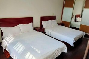 A hotel room with two single beds, wooden headboards, white linens, a nightstand, and a mirror. - Honghelou Hotel, Wuhu (Wuhu)
