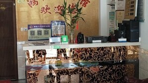 A reception area with a decorative wall, a reception desk, and a display case with items. - Honghelou Hotel, Wuhu (Wuhu)