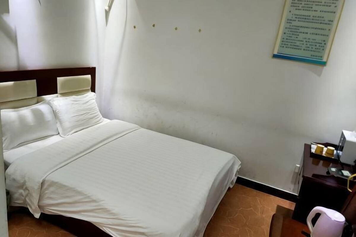 A hotel room with a bed, a nightstand, a desk, and a chair.