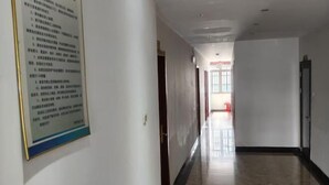 A hallway with a polished floor, a poster on the wall, and doors leading to other rooms. - Honghelou Hotel, Wuhu (Wuhu)