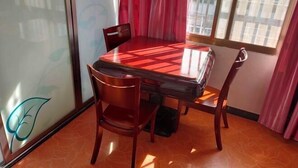 A dining area with a table and chairs, a window with curtains, and a wall with a leaf design. - Honghelou Hotel, Wuhu (Wuhu)