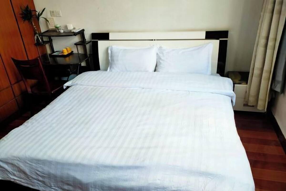 A hotel room with a bed, a desk, and a chair.