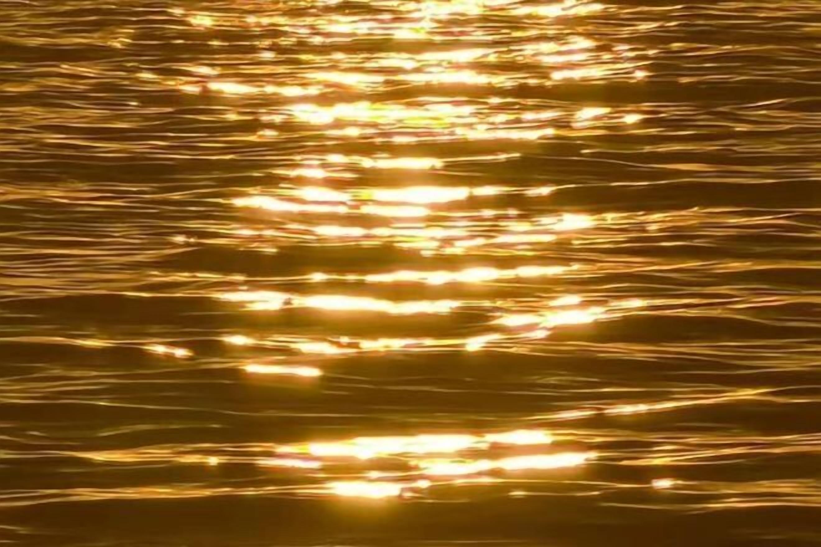 A close-up of water with sunlight reflecting off its surface.