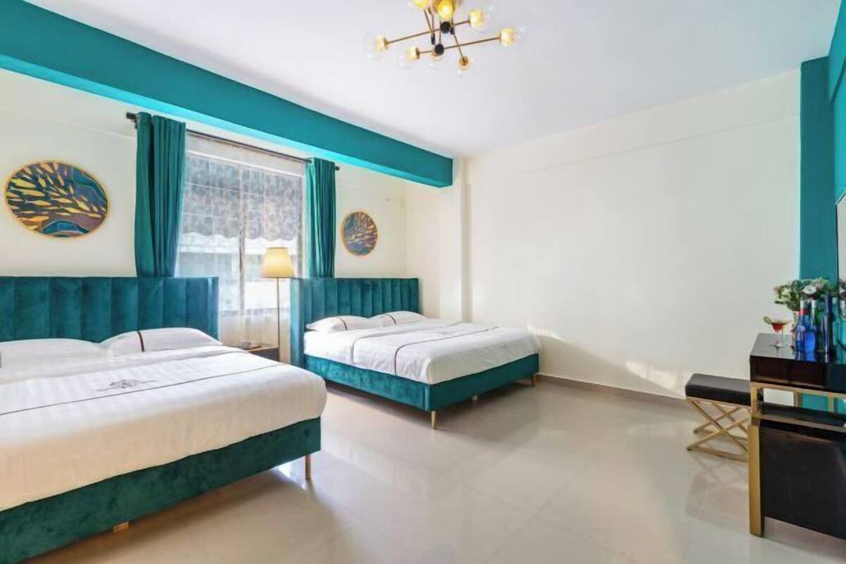 A hotel room with two beds, a desk, and a chandelier.