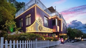 A two-story building with a balcony, a sign reading "Summer Tree House Hotel & Coffee Bar," and a white picket fence in front. - Summer Tree Inn (Sanya)