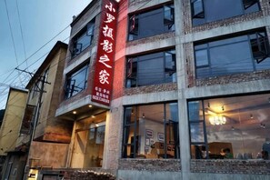 A building with a prominent vertical sign, multiple windows, and a balcony.