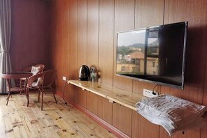 Ein Zimmer mit einer Holzwand, einem daran befestigten Fernseher, einem Holztisch mit einer Bank und einem Stuhl.
