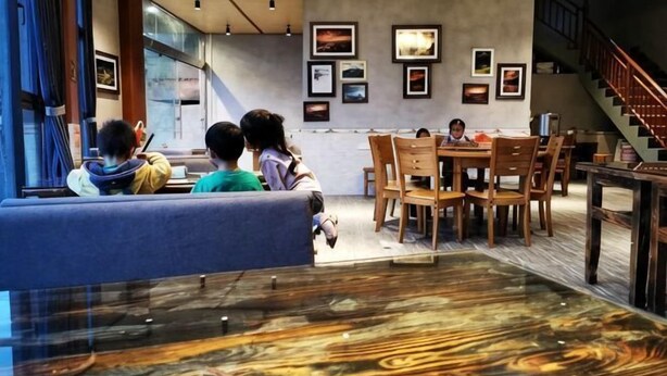 A restaurant with a wooden floor, a blue sofa, and a staircase. - Xiaoluo Ha'ni Titian Sheying Zhijia Hostel (Yuanyang)