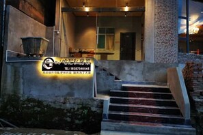 Entrada de hotel con un cartel, una escalera y un muro de ladrillos.